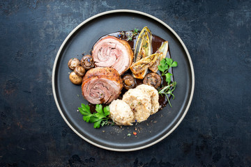 Traditional rolled boar roast with dumpling, fried vegetable and mushroom as top view on a modern...