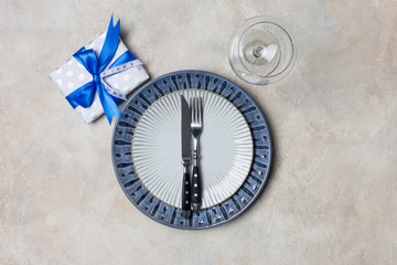 Blue and white plate dish with present box for men with fork and knife, wine glass at white background