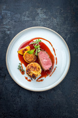 Traditioneller Hischrücken mit schweizer Rösti , Quitte und Orangen Scheiben in Wild Rotwein...