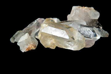 Numerous clear quartz crystal points on black background, surface level and up close on black background.