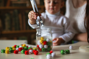 boy Toddler puts colorful soft balls of toy in jar