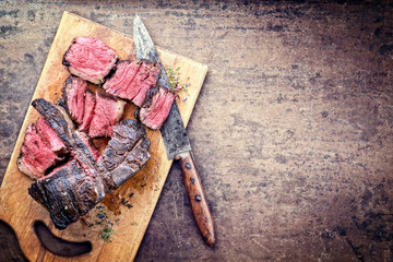Traditional barbecue dry aged wagyu porterhouse steak sliced as top view on a rustic cutting board...