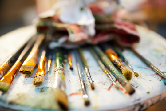 Close up of paintbrushes lying over color palette in art studio, copy space