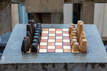 Obraz na płótnie Canvas A set of stone handmade wooden chess on stone table in home outdoor before the game starts