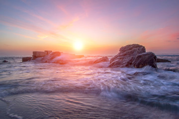 Naklejka premium Bright colorful sunrise on the beach. Sea waves in the bright rays of the sun