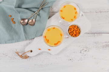 Two high glasses with colorful hot sea buckthorn tea with fresh sea buckthorn berries