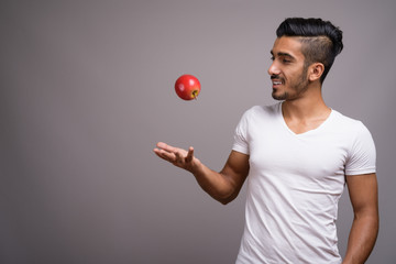 Young handsome Persian man against gray background