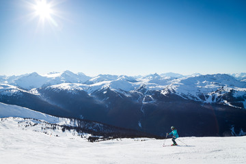 Skiers on a hill at the top of Blackcomb, 7th Heaven, with a view looking toward Whistler on a...