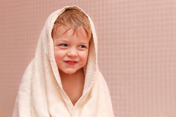 Adorable baby boy sitting under a hooded towel after bath.