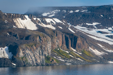 Green cliff in the glacier covered mountains of Franz Josef Land archipelago, Arkhangelsk Oblast, Arctic, Russia