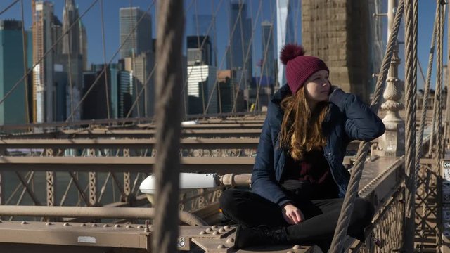 Beautiful girl on Brooklyn Bridge enjoys a sunny day while relaxing