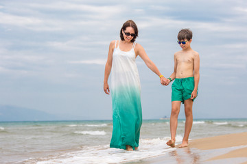 Mother and son having fun on beach during summer holiday vacation
