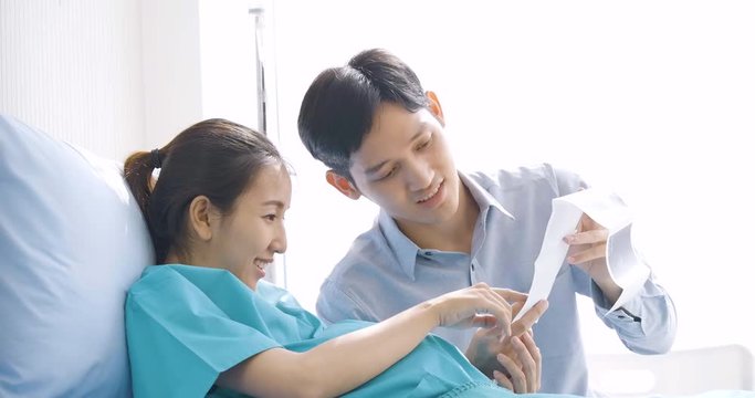 Lovely asian couple excited parents-to-be look at sonogram pictures.