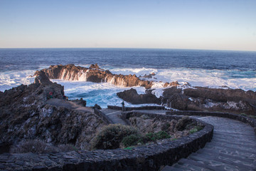 natural pool of volcano stones and the stairs. Waves breaking on the rocks with sunset light in Tenerife, Canary Islands 