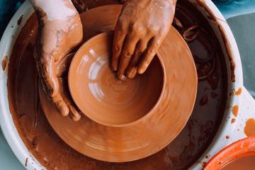 hands of potter creating jar on a circle