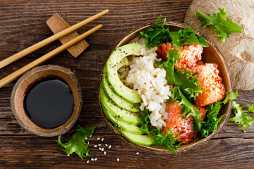 Hawaiian poke coconut bowl with grilled salmon fish, rice and avocado. Healthy food. Top view