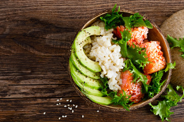 Hawaiian poke coconut bowl with grilled salmon fish, rice and avocado. Healthy food. Top view