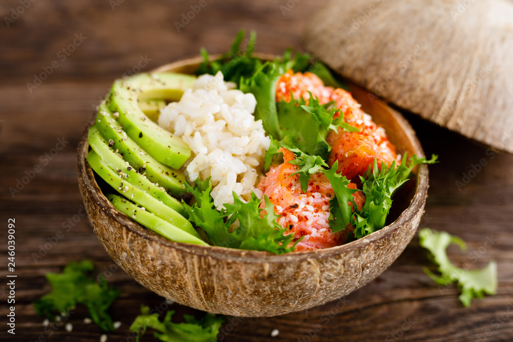 Wall mural Hawaiian poke coconut bowl with grilled salmon fish, rice and avocado. Healthy food