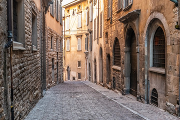 Fototapeta na wymiar Beatiful Old Medieval European narrow empty street of a medieval town on the morning taken in Bergamo, Citta Alta, Italy