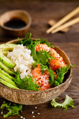 Hawaiian poke coconut bowl with grilled salmon fish, rice and avocado. Healthy food