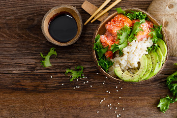Hawaiian poke coconut bowl with grilled salmon fish, rice and avocado. Healthy food. Top view