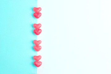 Concept made of heart shaped pink jelly sweets on blue and white background. Top view. Copy space.