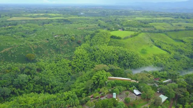 AERIAL: pulling away and panning over the precious Panaca park in Quidio, Colombia, that's been surrounded by coffee plantations.