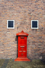 Old brick wall  with red letter box. Look like a face. A chicken face. Translate: Mailbox. Letters. Printed matter. The batch no. Has happened.