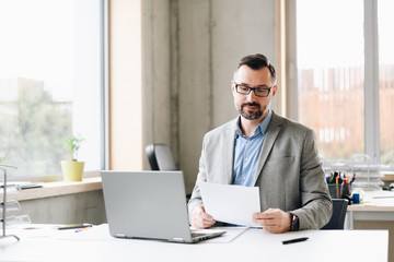 Obraz premium Middle aged handsome businessman in shirt working on laptop computer in office