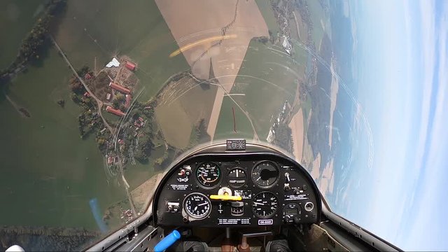pilot's point of view in a sailplane's cockpit tilting left and then flying up above fields, forests, ponds and villages