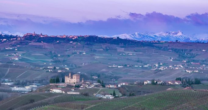 Panoramic view of vineyards and castle of the village of Grinzane Cavour, Langhe monferrato wine area of Piedmont, Italy and in the background alps mountain Monviso with clouds. Time Hyper lapse 4k