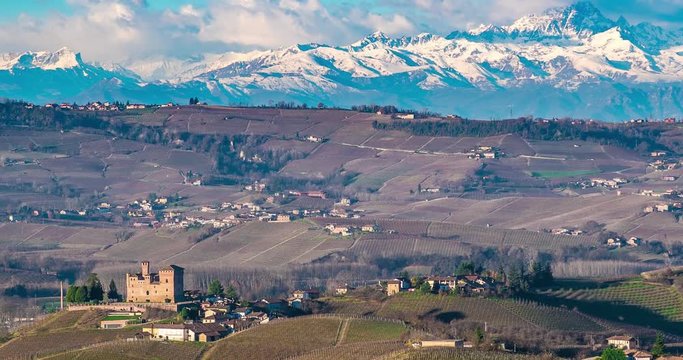 Panoramic view of vineyards and castle of the village of Grinzane Cavour, Langhe monferrato wine area of Piedmont, Italy and in the background alps mountain Monviso with clouds. Time Hyper lapse 4k