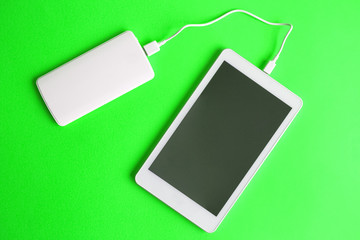 Digital tablet with external battery charger abstract isolated on green.