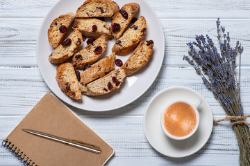 Studio shot of homemade cakes on a wooden tray with  a cup of coffee and notebook with  pen and flowers