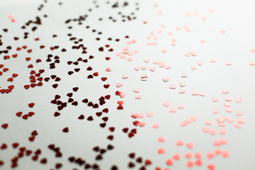  Small red sparkling hearts are scattered on a white background in soft focus. A good shot for an article about love and Valentine's Day or wedding