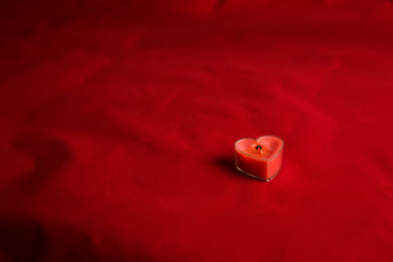  Extinguished red candle in the shape of a heart with smoke from a wick on a red velvet background. Good shot for an article on love and Valentine's Day