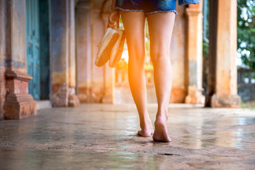 Back of Beautiful Woman holding shoes walking in an abandoned building