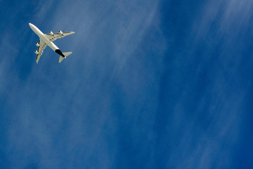 Four engine white plane in the sky on a cold sunny winter day.