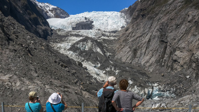 tourists take photographs of franz josef glacier in new zealand