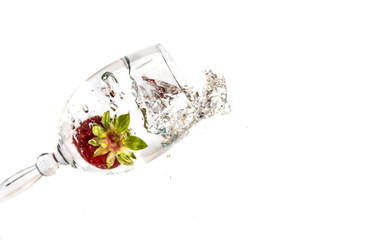 Strawberries fall in a glass of water