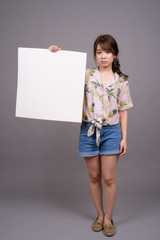 Asian woman holding empty white board with copyspace