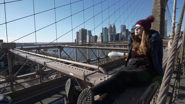 Young beautiful woman on Brooklyn Bridge New York enjoys a wonderful sunny day