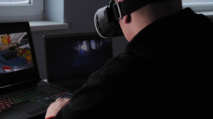 Young guy (male) player in virtual glasses plays (relaxes) against him 2 game monitors, he moves his hands seeing the movement with glasses. Concept of: Lifestyle, Underworld, 3d, Virtual reality