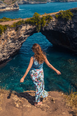 girl on the cliff shore looks at the ocean