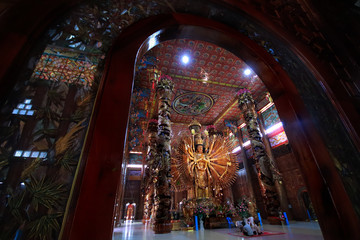 Obraz premium Take photo man and woman with large Guan Yin Bodhisattva carved from wood 12 meters high in Wat Metta Photiyan
