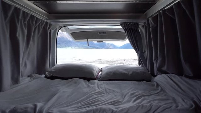 SLOWMO - Interior of motorhome bed with pillows and blankets by Lake Wakatipu, Queenstown, New Zealand with snowcapped mountains in background