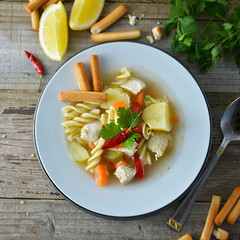 Chicken soup with noodles and vegetables, rustic wooden background. Healthy homemade food. Top view. Square image.
