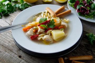 Chicken soup with noodles and vegetables, rustic wooden background. Healthy homemade food.