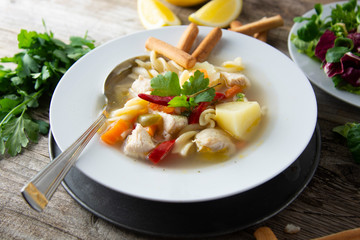 Chicken soup with noodles and vegetables, rustic wooden background. Healthy homemade food.