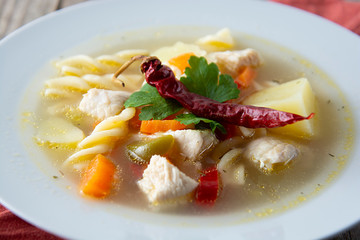 Chicken soup with noodles and vegetables, rustic wooden background. Healthy homemade food. Top view. Square iamge.